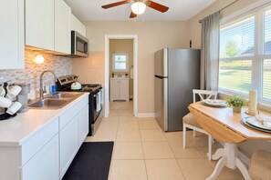 A modern kitchen with white cabinetry, a stainless steel refrigerator, a wooden dining table, and a ceiling fan. - Premium studio haven close to Louisville spots! (Clarksville)