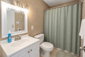 A bathroom with a white sink, mirror, and toilet. - Premium studio haven close to Louisville spots! (Clarksville)