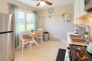 A modern kitchen with a stainless steel refrigerator, a dining table with chairs, a stove, and a sink. - Premium studio haven close to Louisville spots! (Clarksville)