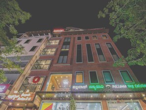A multi-story building with a mix of brick and glass facades, featuring illuminated signage for businesses. - Hotel O Briklane (Bengaluru)