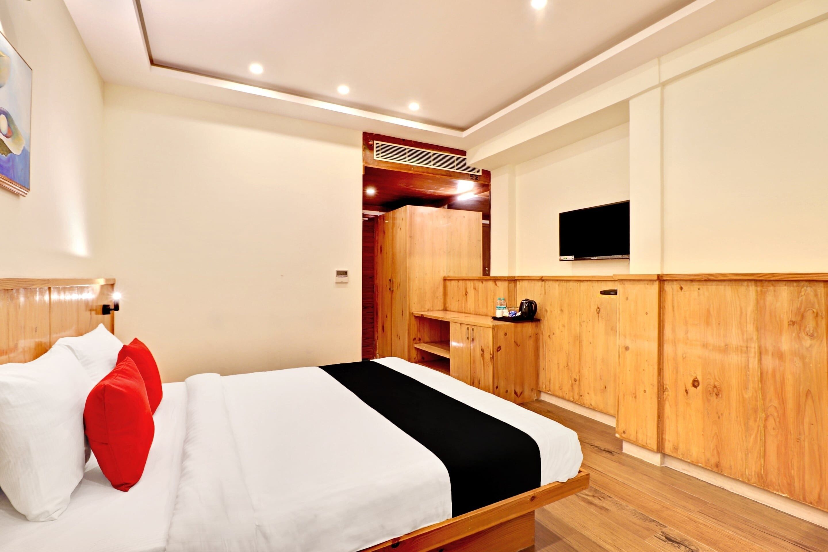 Una habitación de hotel con una cama, un televisor montado en la pared y paneles de madera.