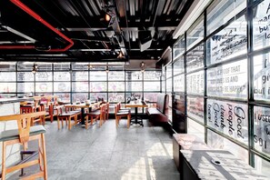 A restaurant interior with wooden tables and chairs, large windows with motivational quotes, and a modern industrial ceiling design. - Hotel O Briklane (Bengaluru)