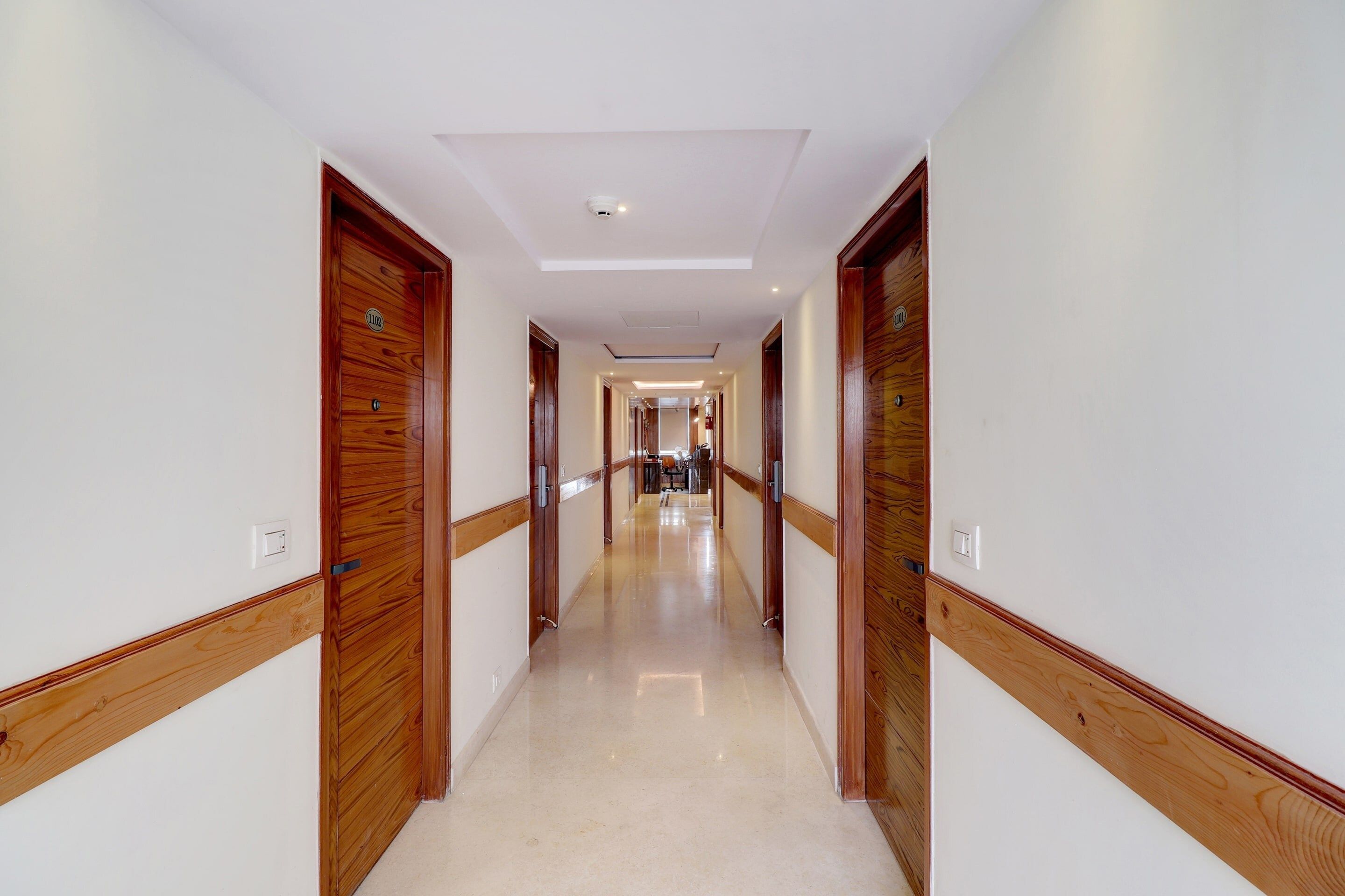 Un pasillo de hotel con puertas de madera y suelo de baldosas.