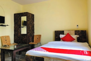 Une chambre d’hôtel équipée d’un lit, d’un bureau, d’une chaise, d’un miroir et d’un téléviseur.