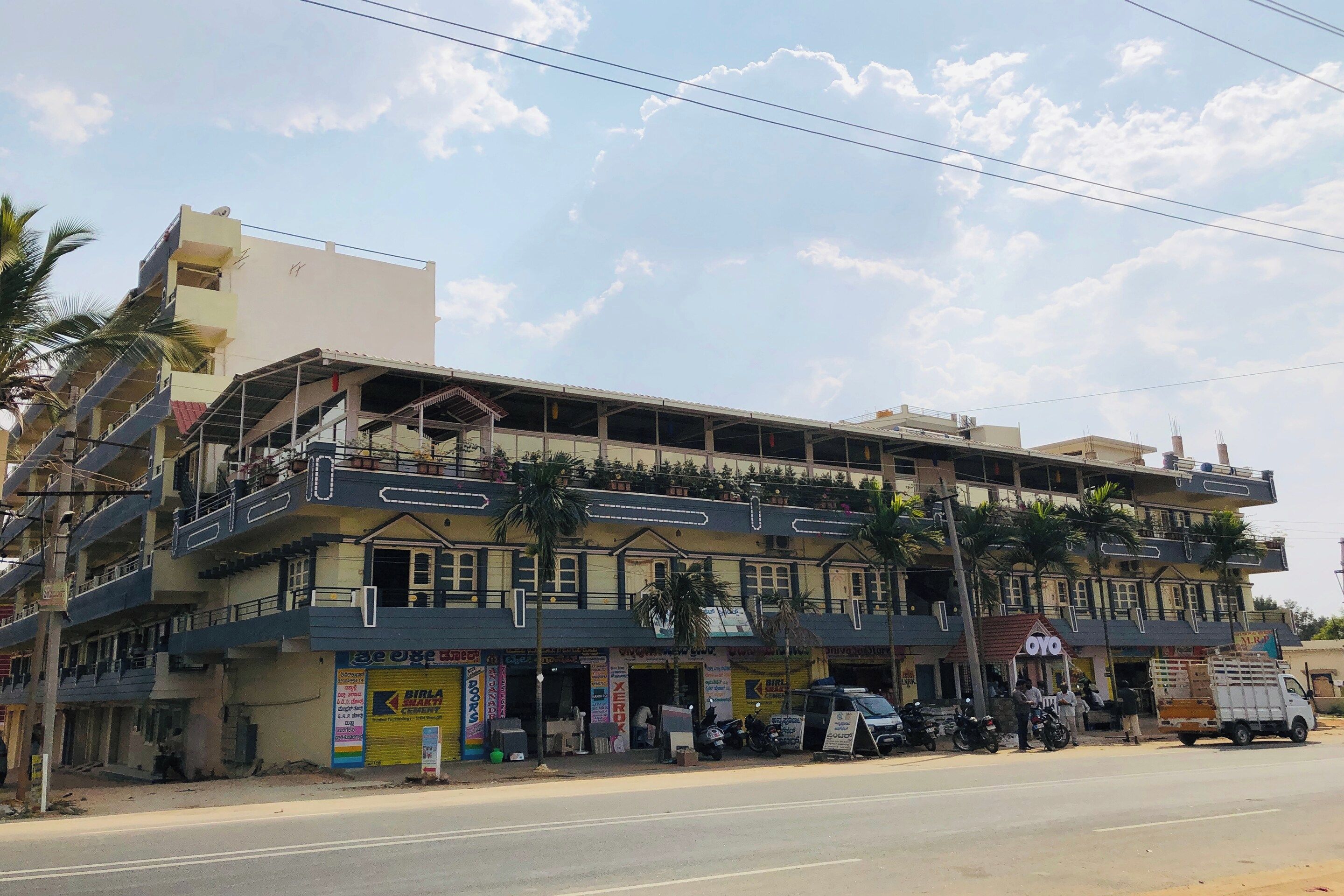 A multi-story building with commercial shops on the ground floor, a covered upper level, and a flat roof with visible structural beams.