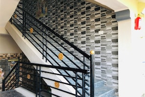 Un escalier avec des rampes noires et des murs à motifs de pierre.
