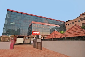 A modern building with a glass facade and a red roof. - Hotel O JP PALACE (Doddaballapura)