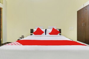Quarto de hotel com cama, mesa de cabeceira, guarda-roupa e interruptor de luz na parede.