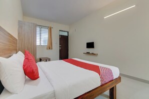A hotel room with a bed, a television, and a window with blinds. - Hotel O NCR Rooms (Bangalore)