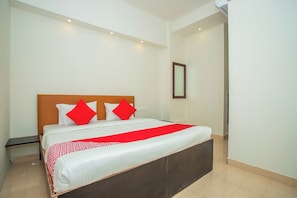 Una habitación de hotel con una cama grande, cabecera de madera y una manta roja.