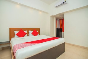 Una habitación de hotel con una cama grande, un cabecero de madera y una colcha roja y blanca.