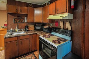A kitchen with wooden cabinets, a stove, a microwave, and a sink. - Adirondack Mountain Lakefront (Northville)
