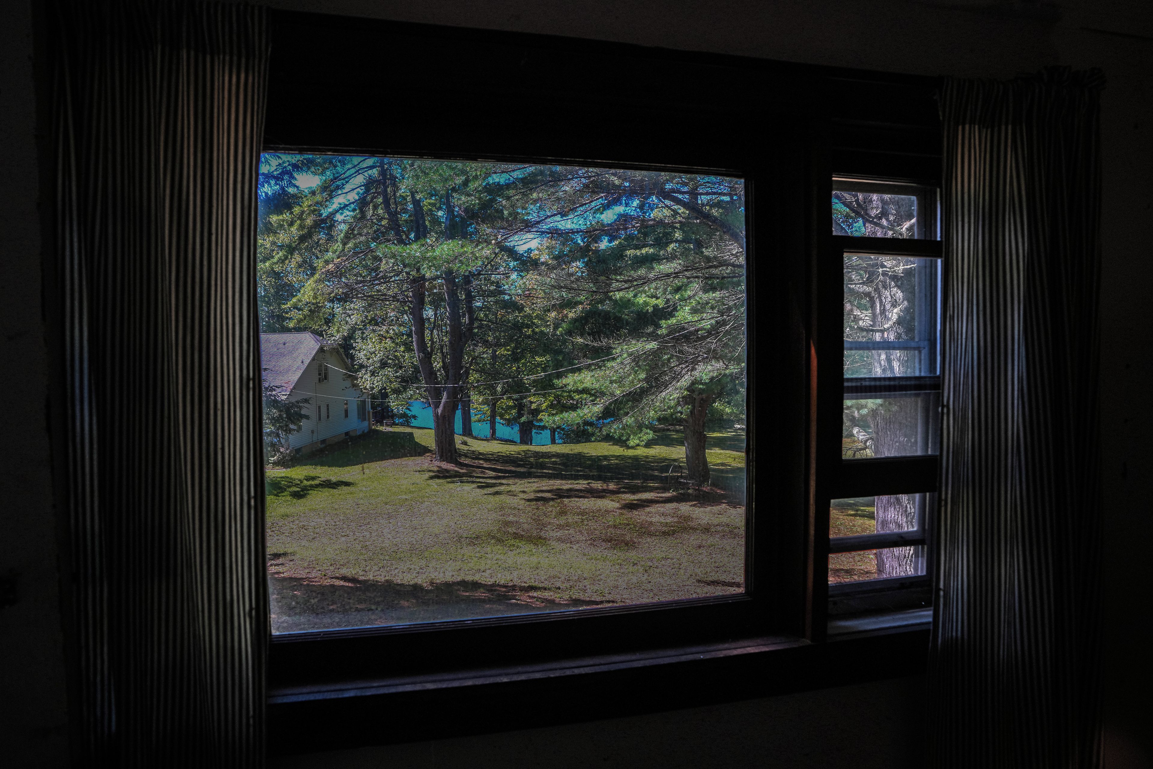 Una ventana con vista a una casa y árboles.