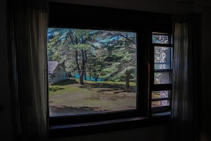 A window with a view of a house and trees. - Adirondack Mountain Lakefront (Northville)