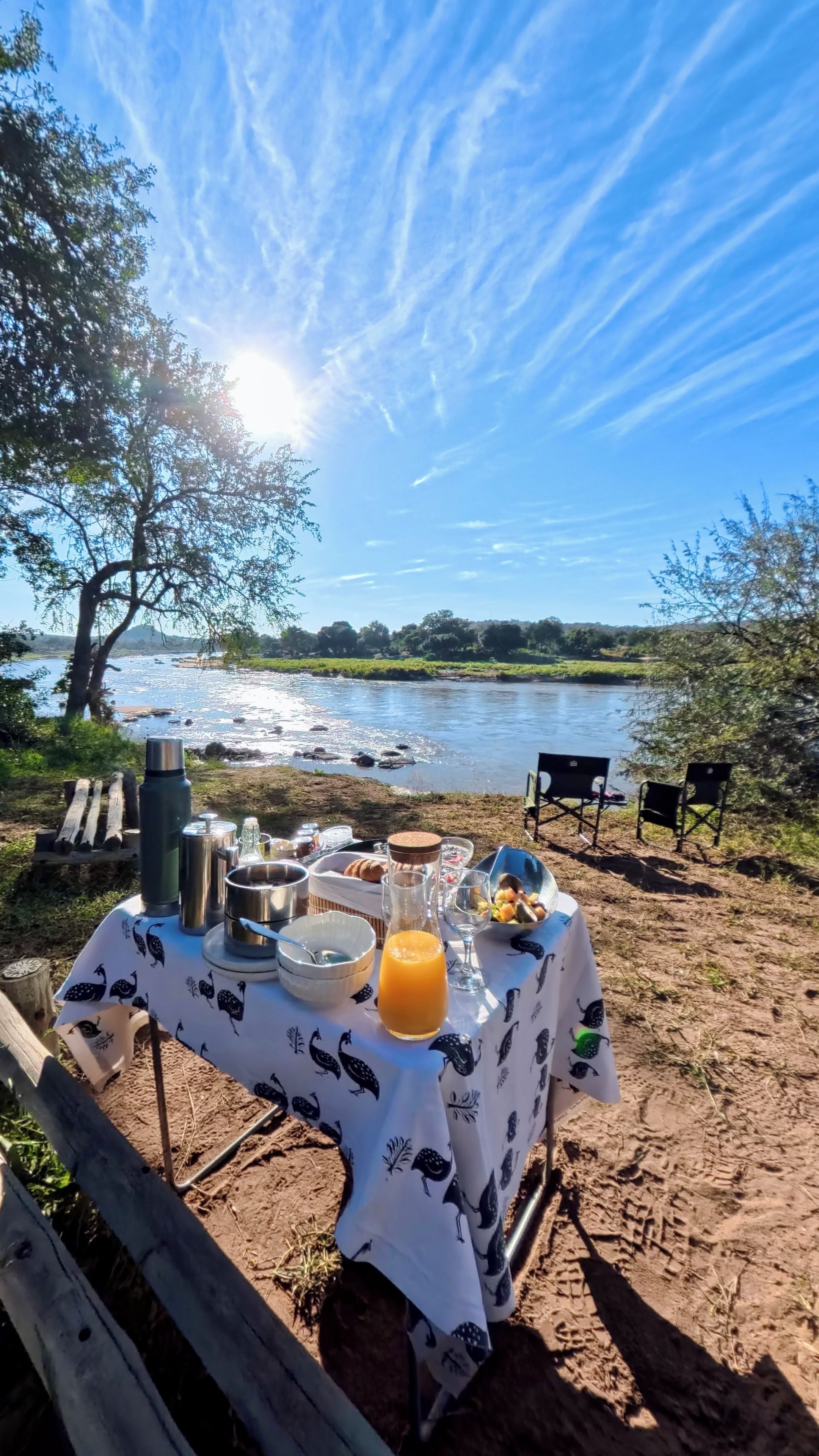 Un espace de restauration en plein air avec une table dressée pour deux personnes, donnant sur une rivière.