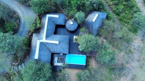 An aerial view of a property with a large, irregularly shaped building, a swimming pool, and surrounding vegetation.