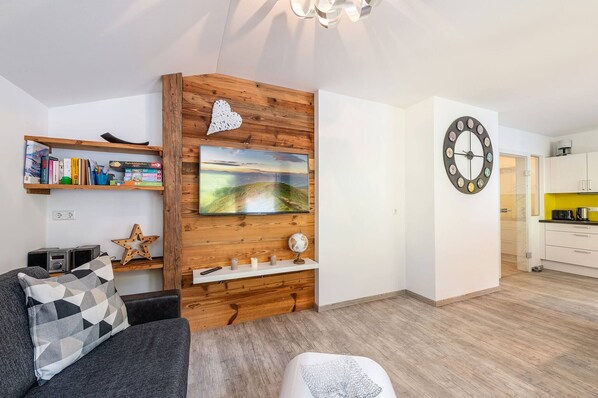 Un salon moderne avec un mur d’accent en bois, un téléviseur fixé au mur, un globe terrestre et une horloge.