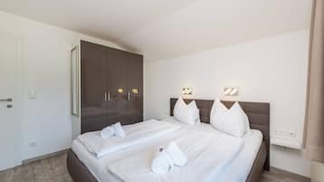 A hotel room with a bed, a wardrobe, and a bedside table.