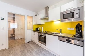 A modern kitchen with white cabinets, a yellow backsplash, stainless steel appliances, and a built-in oven.