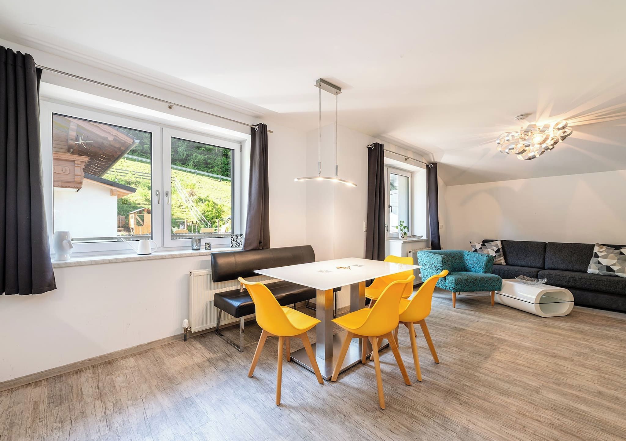 Una sala moderna con comedor, ventanas amplias y un sofá.