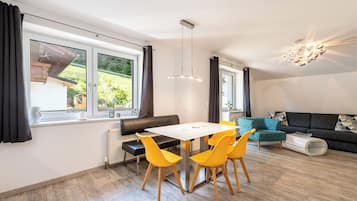 Una sala moderna con comedor, ventanas amplias y un sofá.