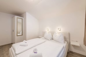 Ein Hotelzimmer mit zwei Einzelbetten, einem Spiegel, Nachttischlampen und einem kleinen Nachttisch.