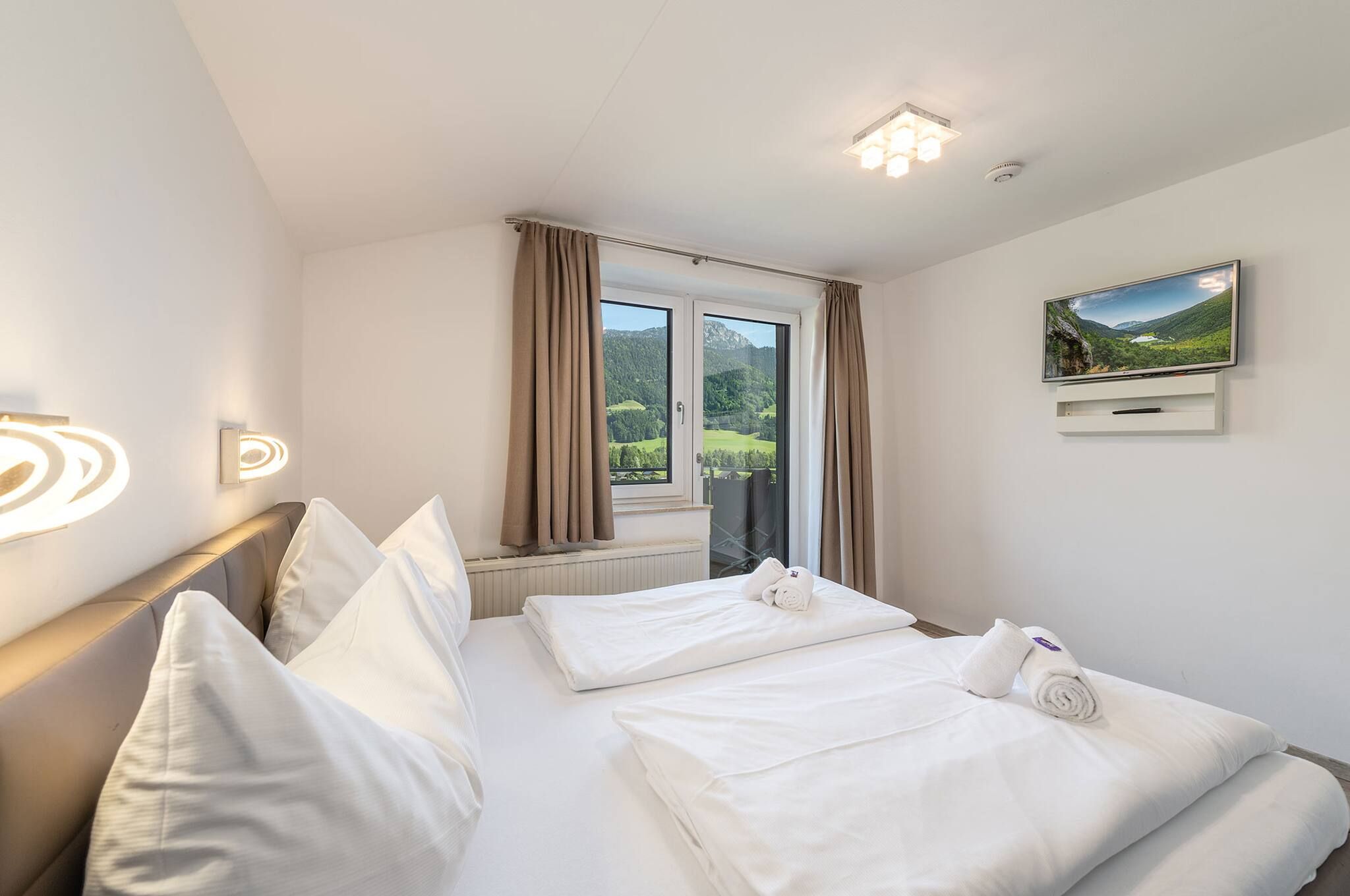 Ein Hotelzimmer mit einem Bett, einem Fernseher und einem Vorhangfenster.