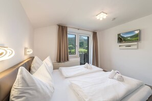Ein Hotelzimmer mit einem Bett, einem Fernseher und einem Vorhangfenster.