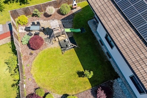 Vista aerea di una proprietà residenziale con giardino recintato, area salotto all'aperto e pannelli solari.