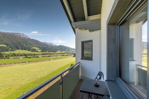 A balcony with a view of a green field and mountains.