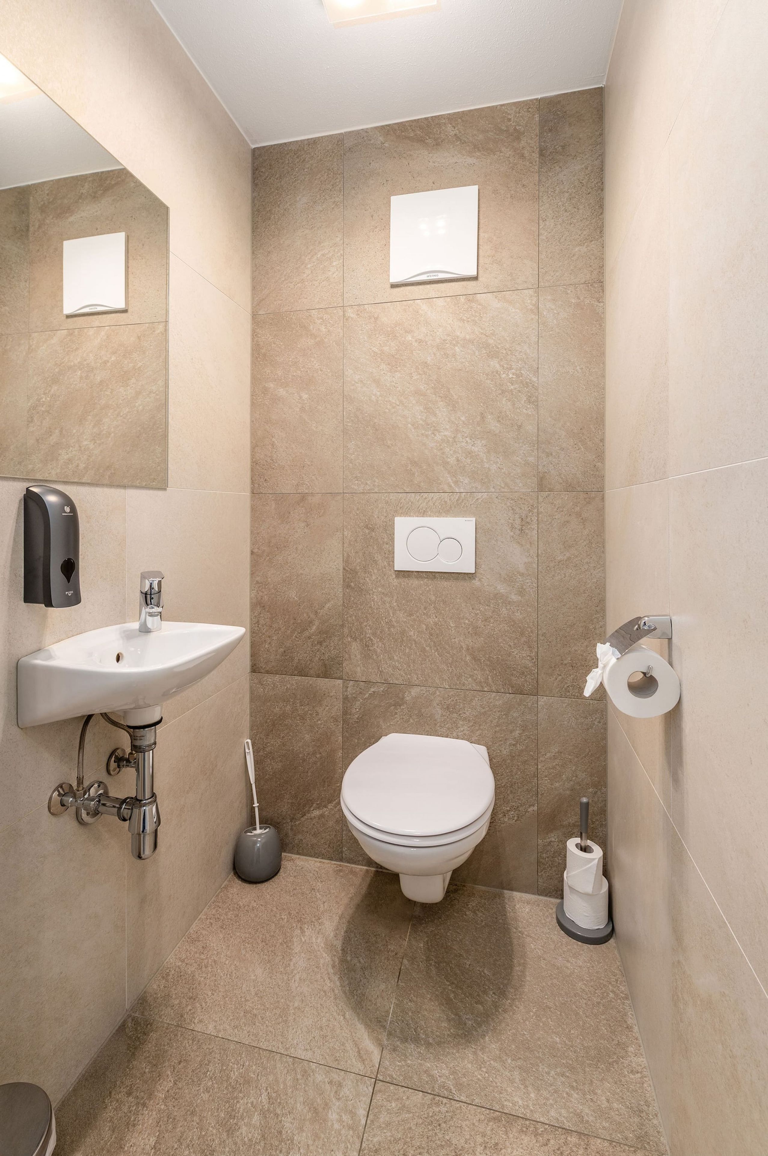 A bathroom with a sink, toilet, and hand dryer.