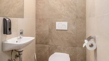 A bathroom with a sink, toilet, and hand dryer.