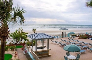 Un complexe hôtelier en bord de mer, doté de chaises longues, de parasols et d’un belvédère offrant une vue sur l’océan.