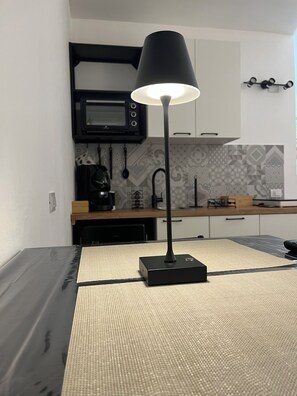 Eine moderne Küche mit Mikrowelle, Kaffeemaschine und einer schwarzen Lampe auf einem Tisch.