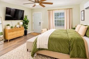 A bedroom with a bed, a TV, a dresser, and a plant. - Exclusive Queen Suite: Louisville City Escape! (Clarksville)