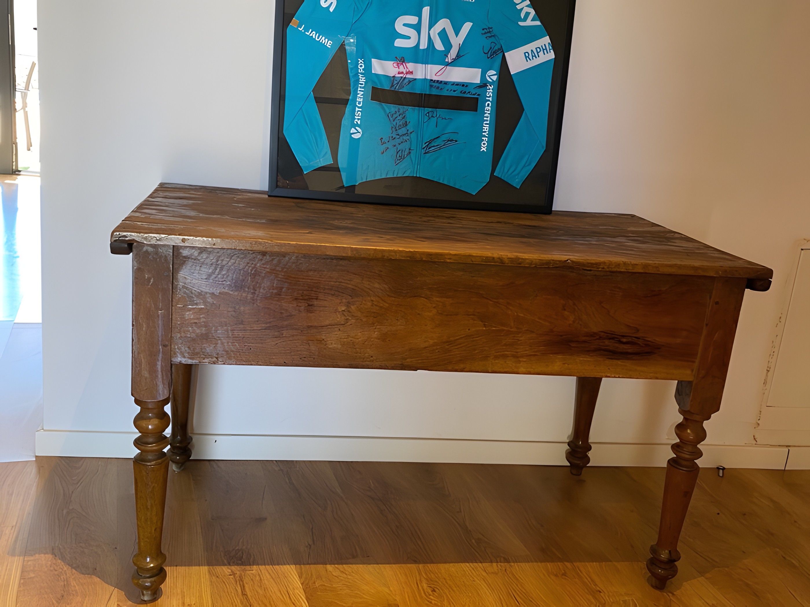 A wooden table with a framed item on top.
