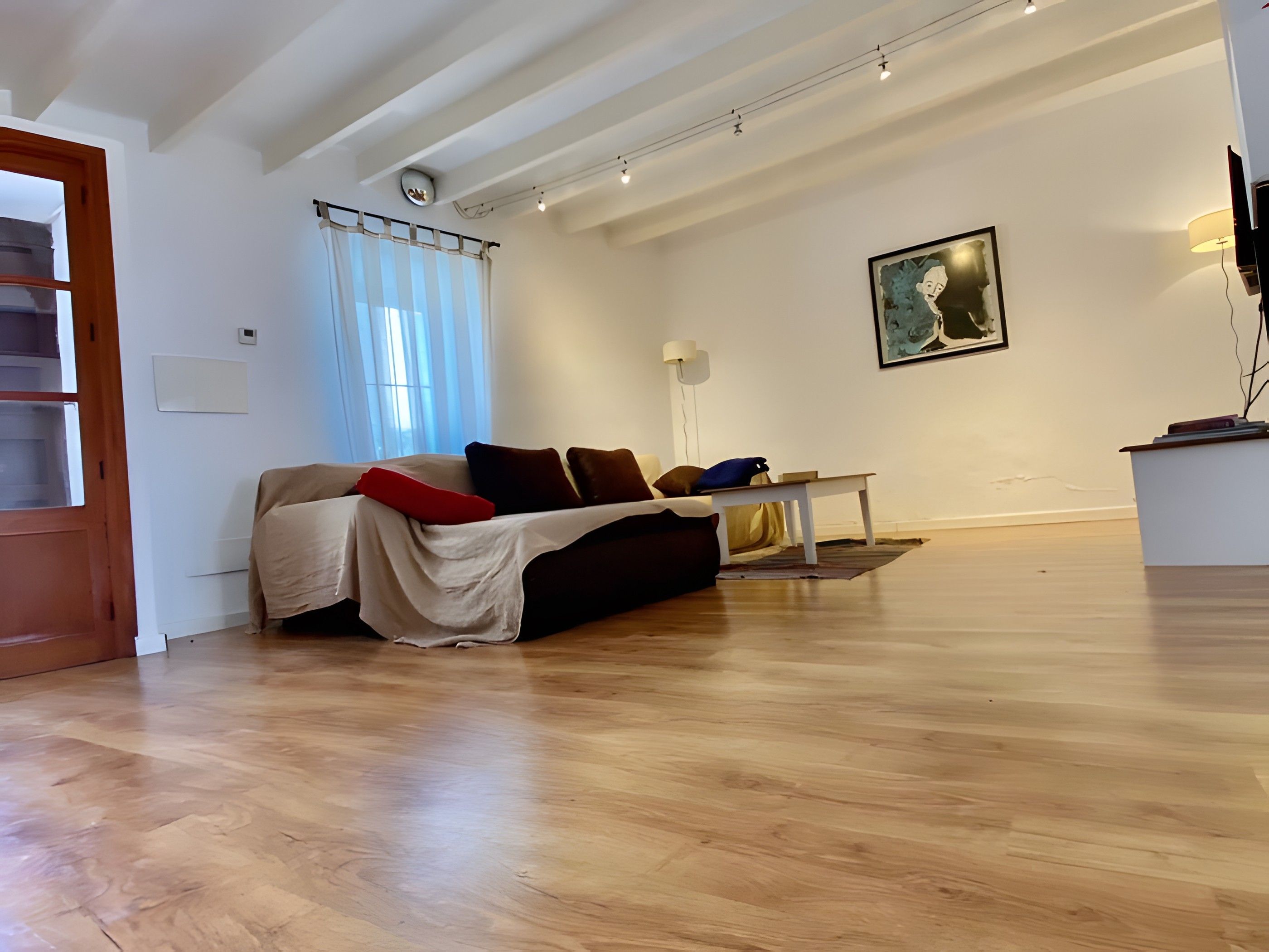 Un salon avec un canapé, une table et un tableau accroché au mur.