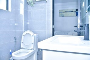 Et stilfuldt badeværelse med toilet, håndvask og bruseområde.
