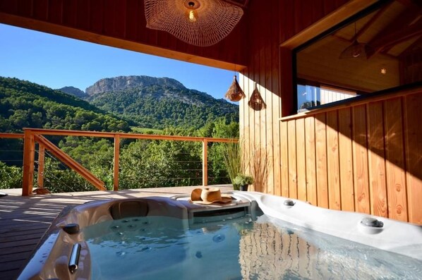 Una terraza de madera con un jacuzzi y vistas a la montaña.