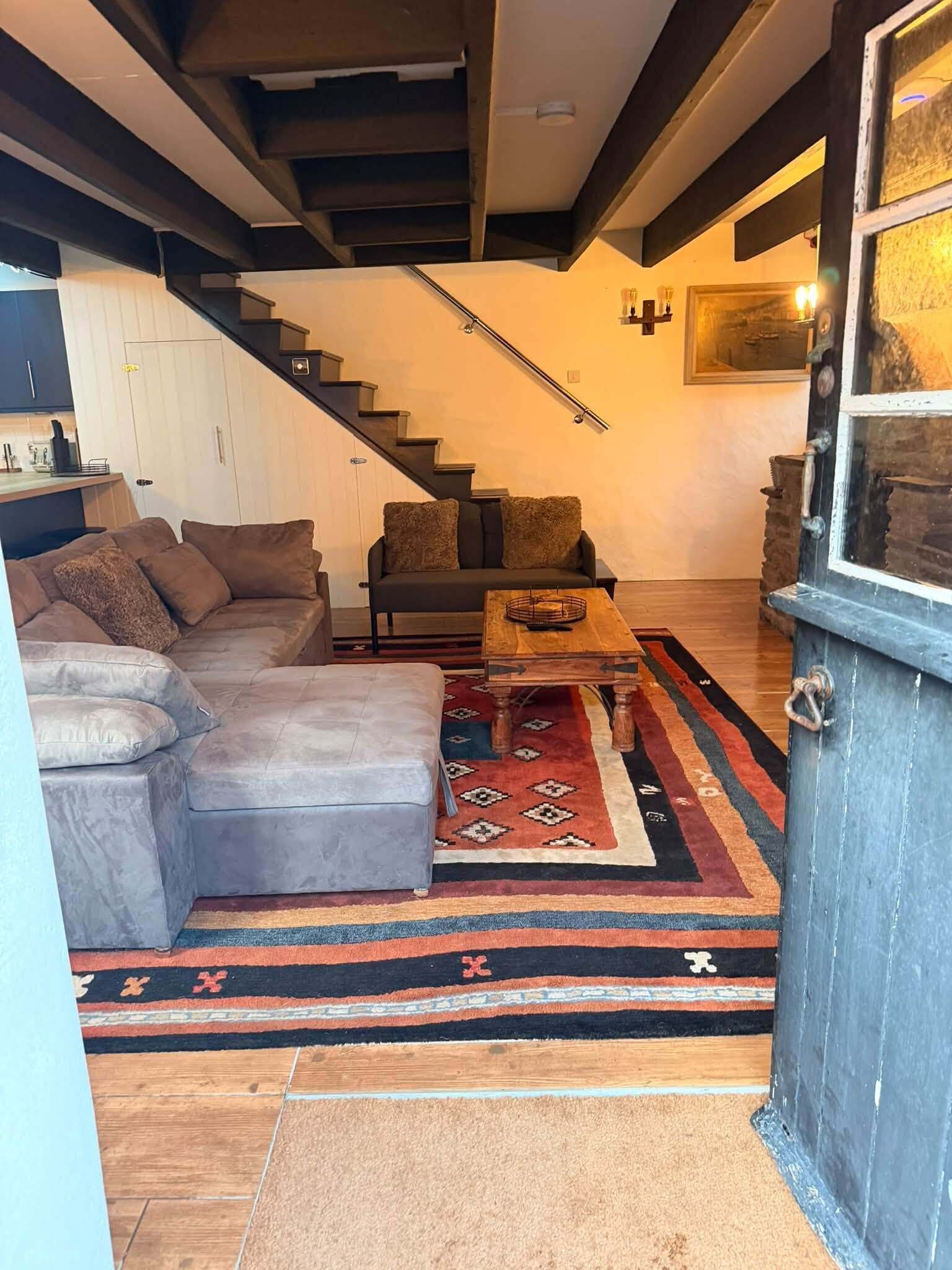 Una sala moderna con un sofá seccional, una mesa de centro y una alfombra estampada.