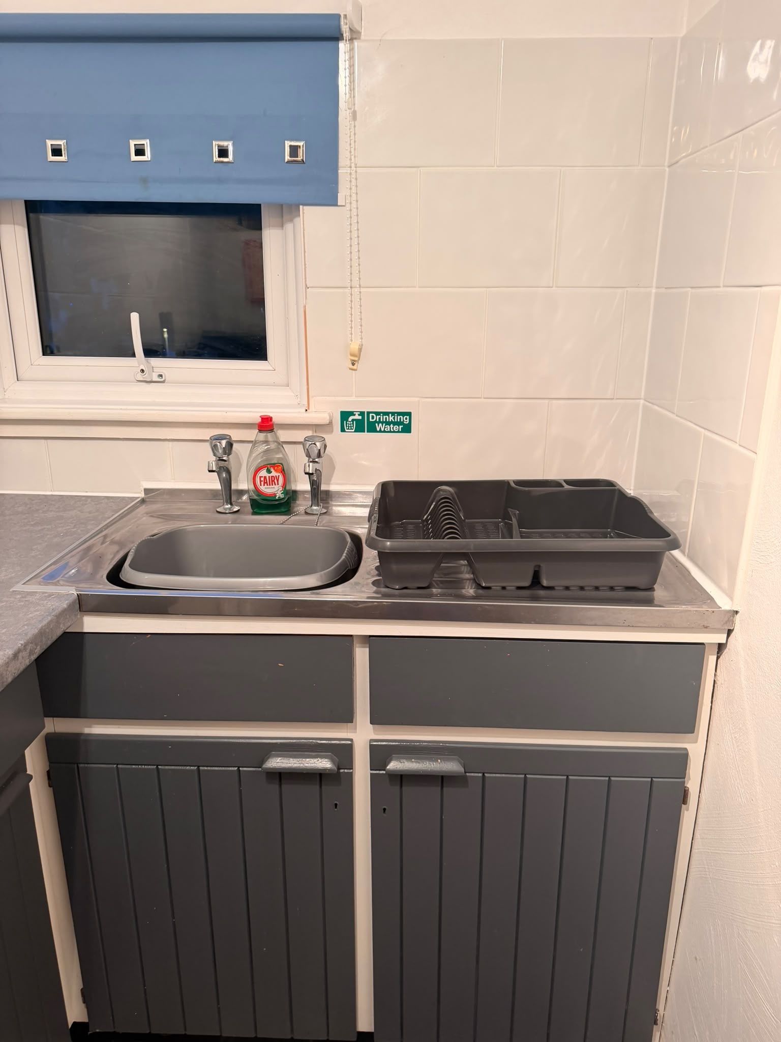 Une cuisine équipée d’un évier, d’une fenêtre et d’un panneau indiquant un point d’eau potable.