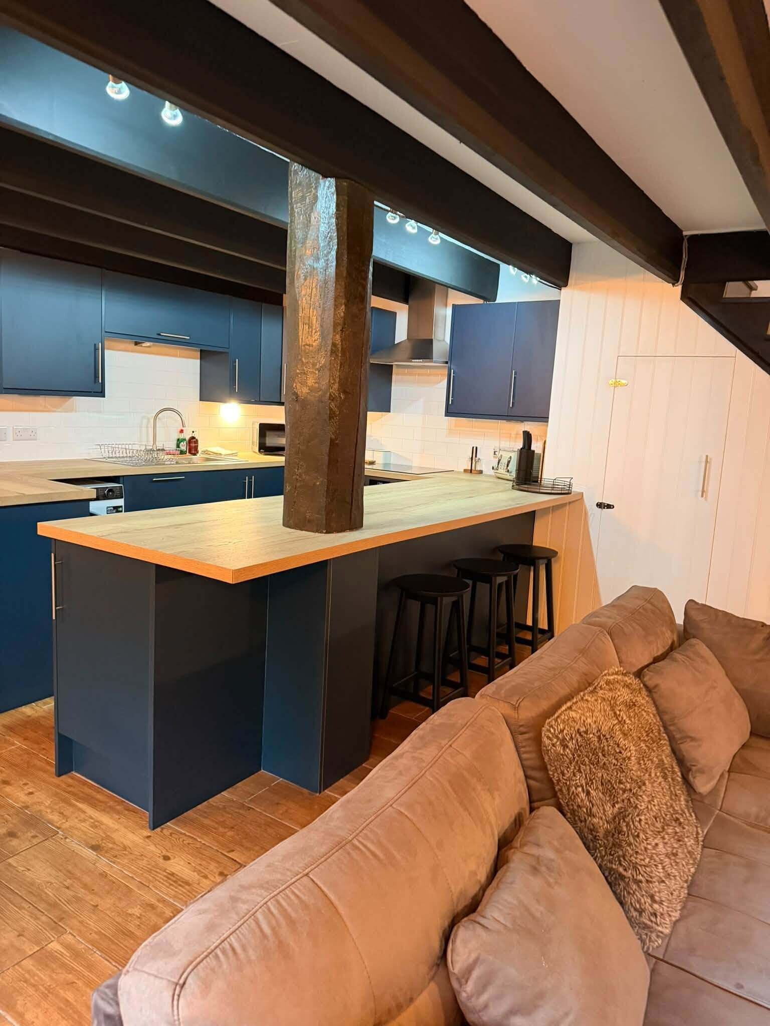 Una cocina moderna con armarios azul oscuro, una isla de madera y una estufa empotrada.