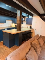 Una cocina moderna con armarios azul oscuro, una isla de madera y una estufa empotrada.