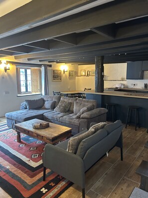 A living room with a sectional sofa, a coffee table, and a rug. - Crumplehorn Inn & Mill (Looe)