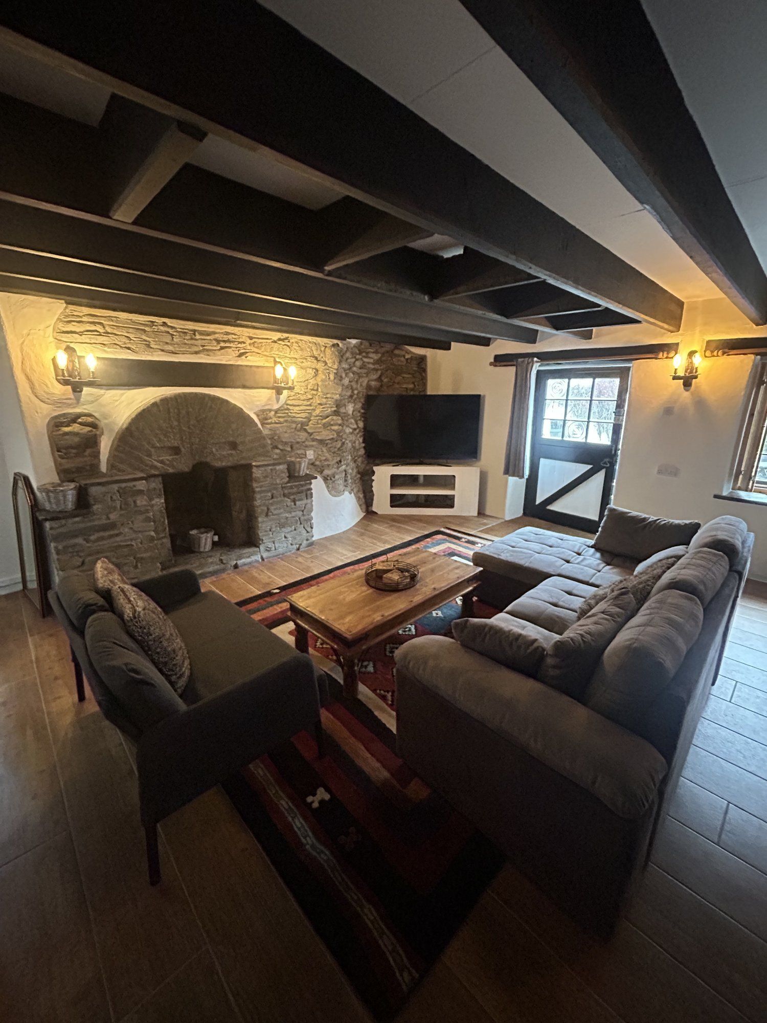 Una sala de estar acogedora con chimenea de piedra, un sofá, una mesa de centro y un televisor.