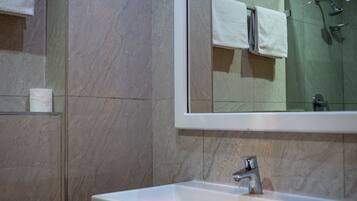 A bathroom with a white sink, a mirror above it, and a shower area in the reflection.