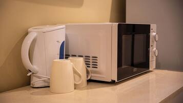 Un four à micro-ondes et une machine à café sont posés sur un plan de travail.