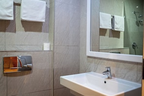 A bathroom with a white sink, a mirror, and a shower.