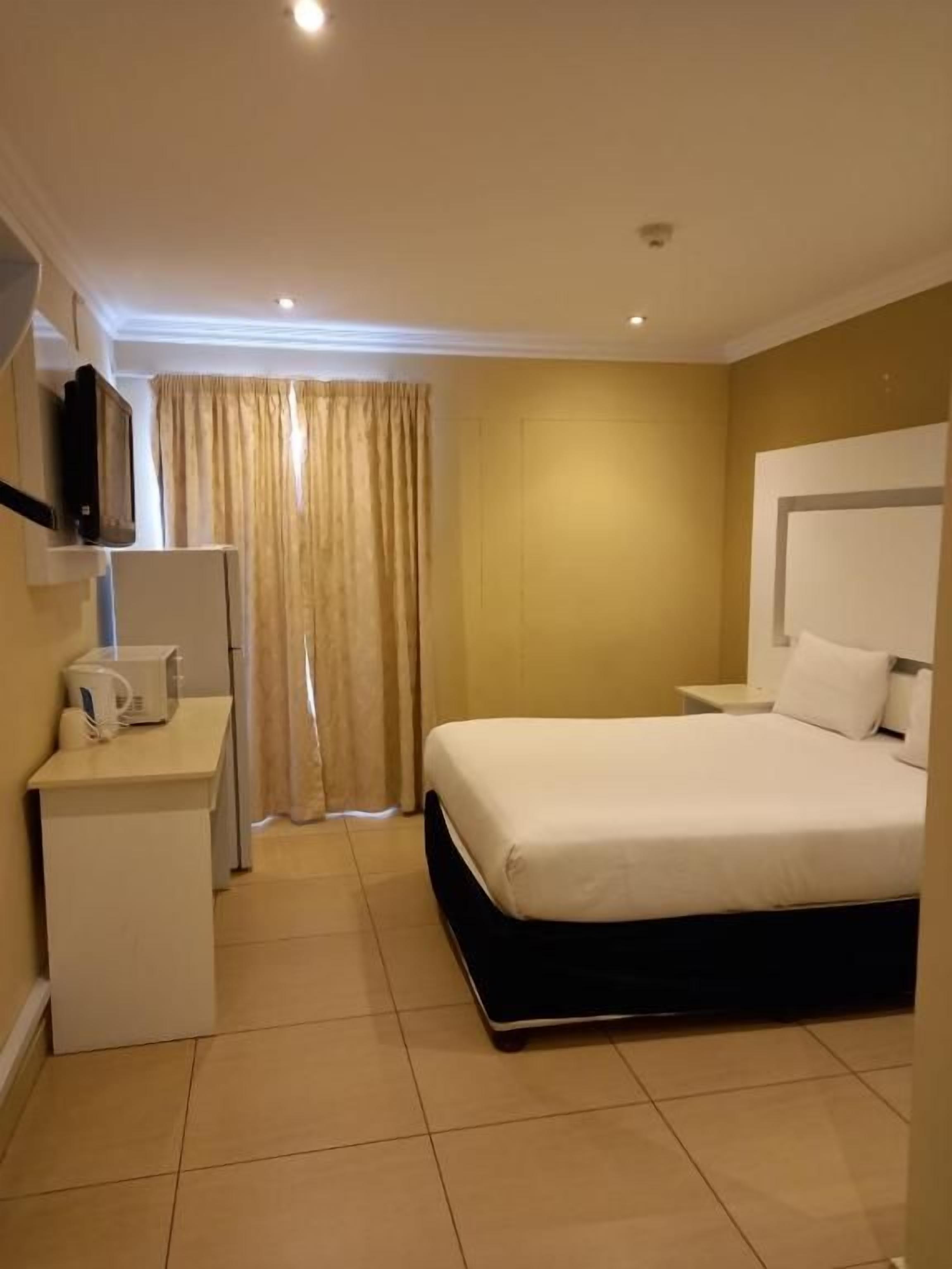 Habitació d'hotel amb un llit, una taula de nit i una televisió penjada a la paret.
