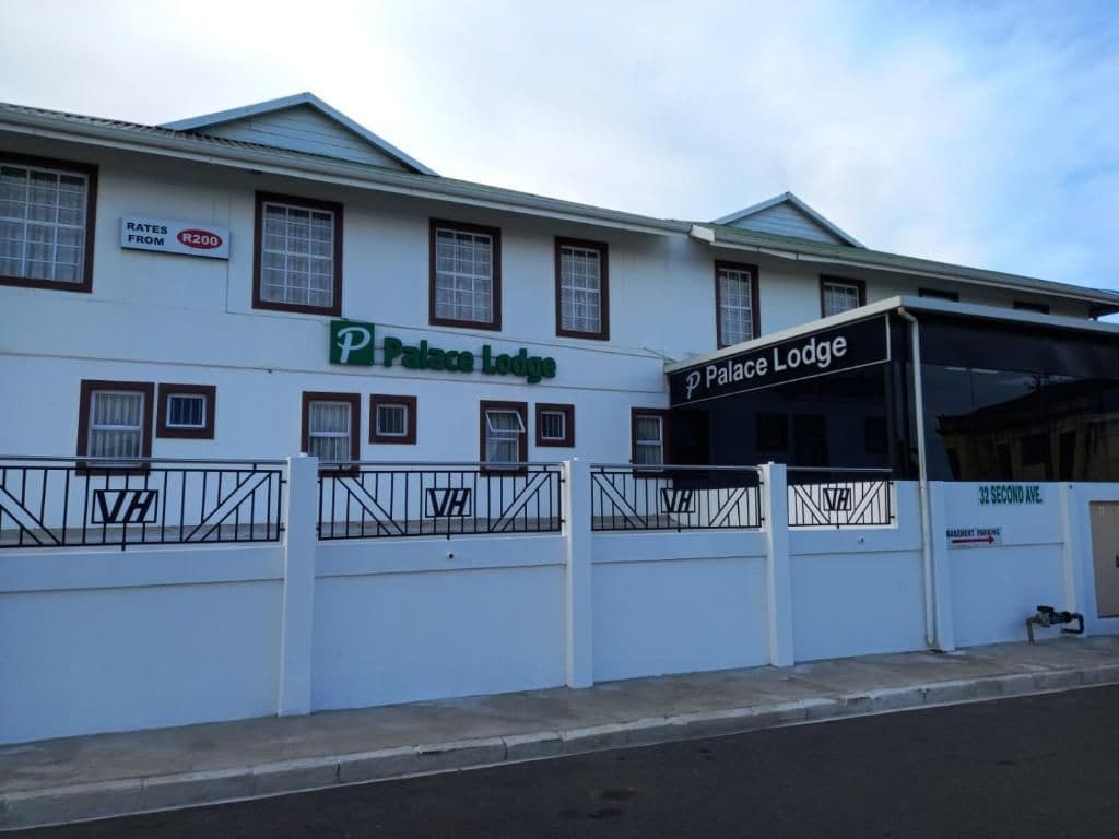 Un edificio blanco con un cartel que indica 'Palace Lodge' y un letrero de estacionamiento que muestra tarifas desde 200 rands.